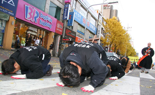 삼보일배에 참가한 참가자들이 차가운 아스팔트에 절을 하고 있다. 